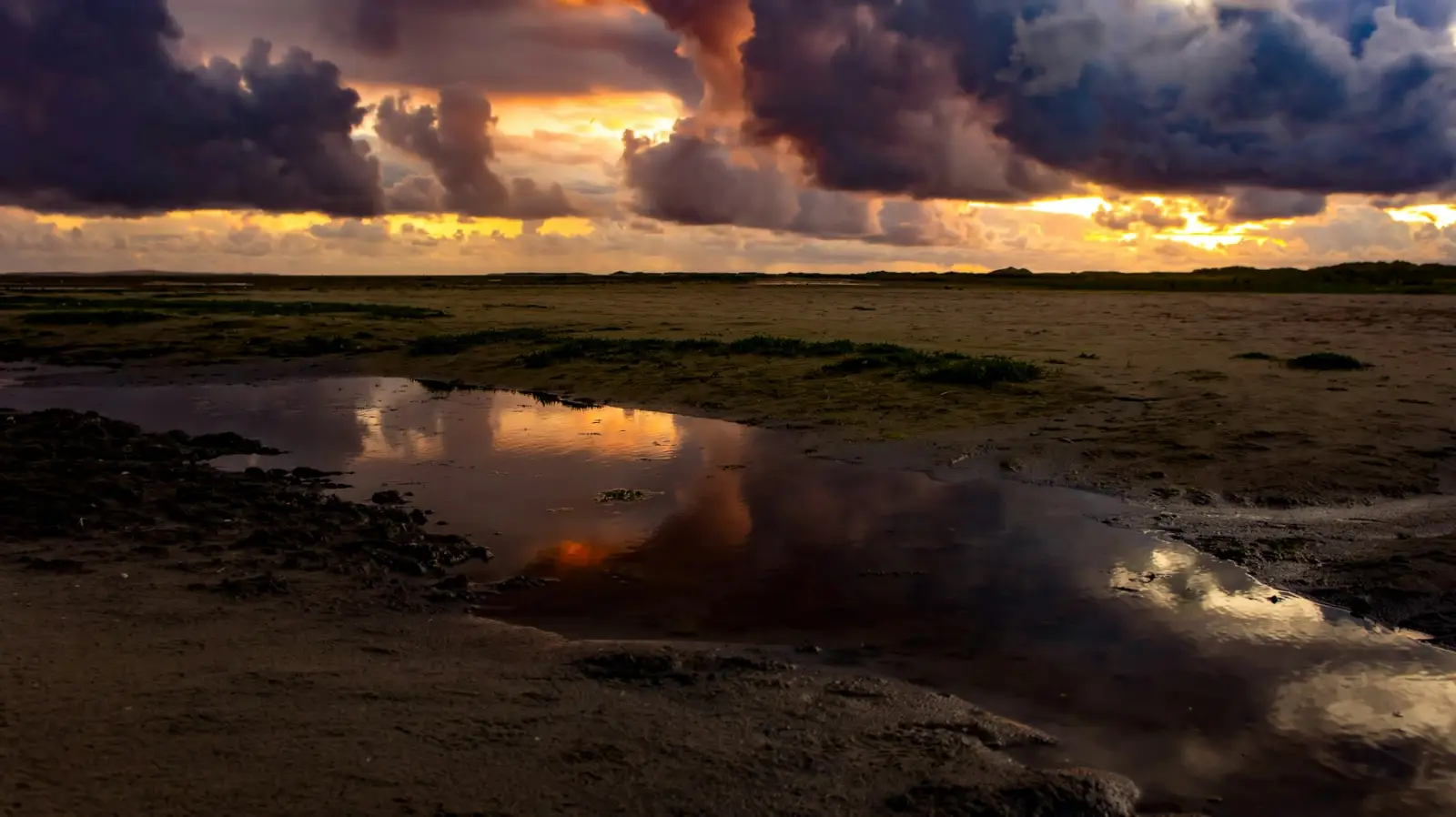 Zonsondergang boven de kwelder, de lucht spiegelt in het water